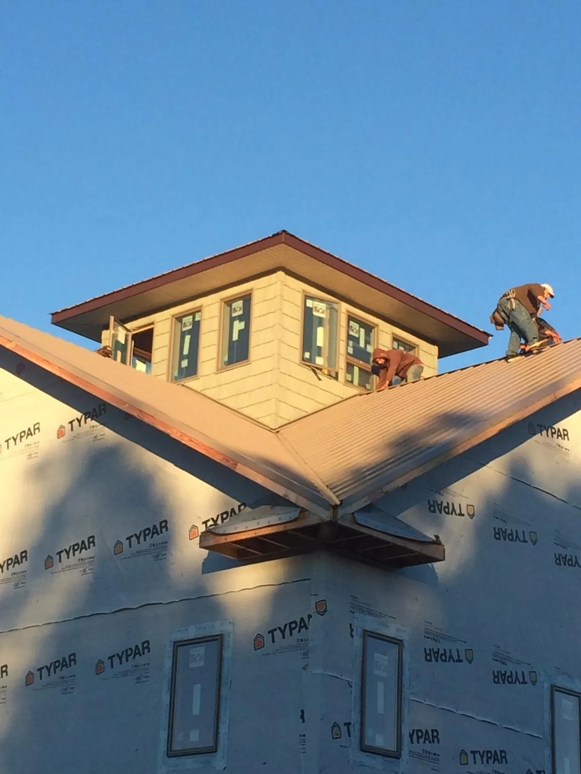 Roofers working around a rooftop cupola on a new metal roof at sunset — Roof Waterproofing in Lapwai by Roofing Brothers
